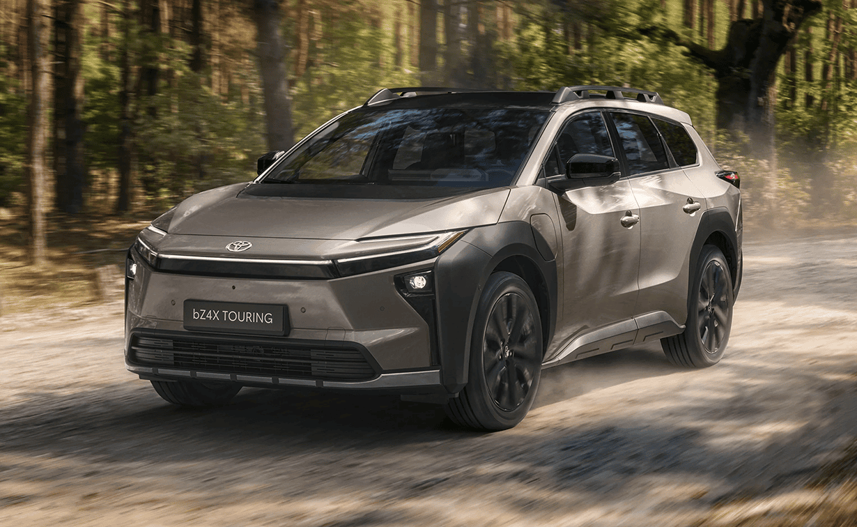 Toyota bZ4X Touring in brons op de weg in bosrijke omgeving 