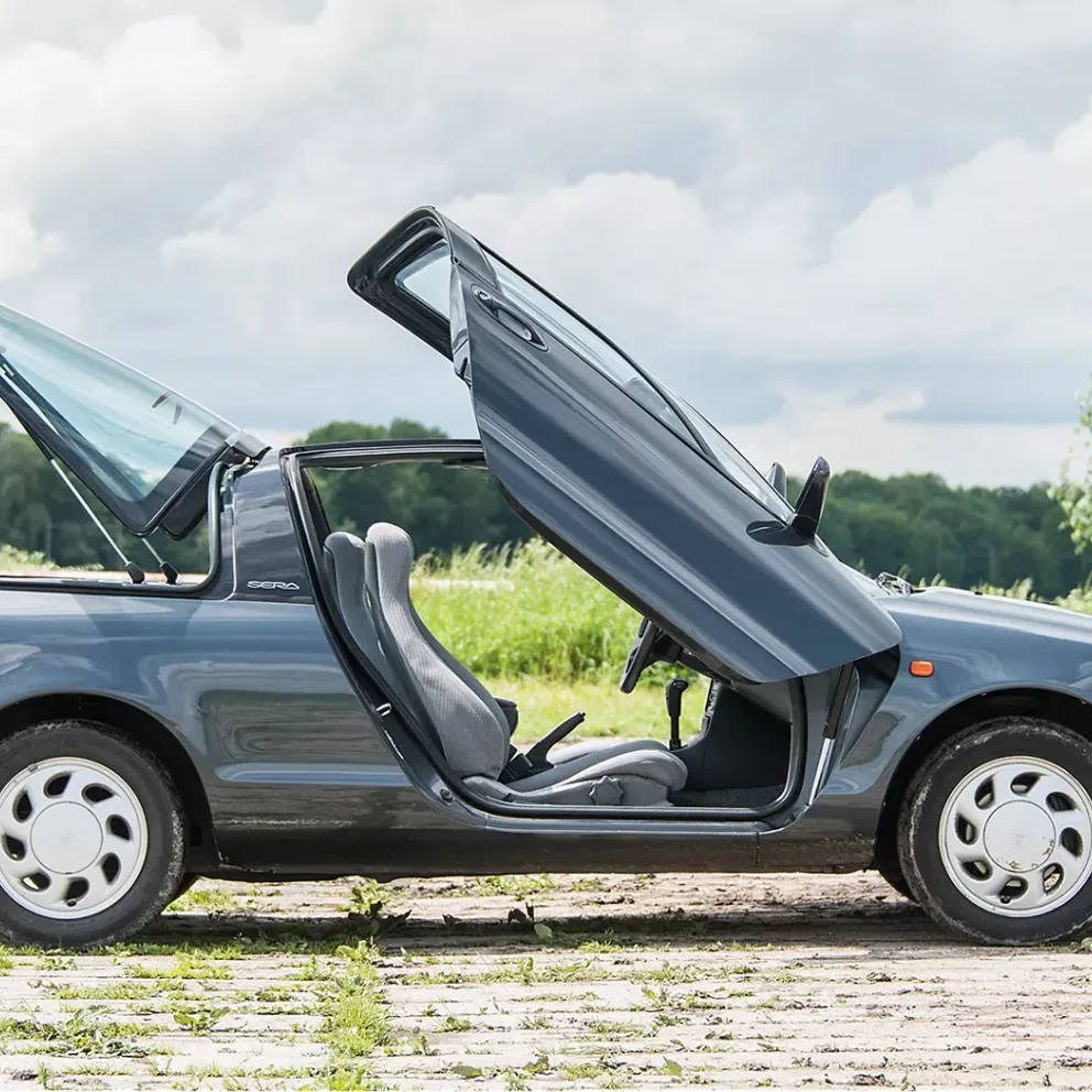 Close-up van de Toyota Sera met de iconische vleugeldeuren geopend, een kenmerkende eigenschap van de auto.
