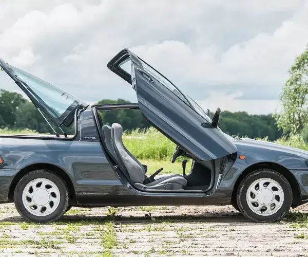 Close-up van de Toyota Sera met de iconische vleugeldeuren geopend, een kenmerkende eigenschap van de auto.